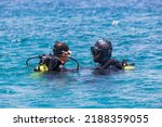 Small photo of Instructor giving scuba diving lessons to a kid. Scuba diving Instructor teaching a little boy to dive. Diver course. Two scuba divers in shallow Sea. Divers dressed in diving suit, aqualung.