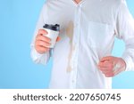 Small photo of A man showing a dirty coffee stain on shirt a blue background. Spoiled clothes. Dirty coffee stain on clothes. daily life stain concept. High quality photo