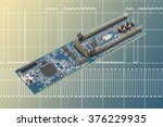 Small photo of Programming hardware evaluation board in front of digital signal oscillogram