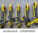 Several yellow e-scooters stand in a row for rent. Scooters are available for rent. Walk around the city light.