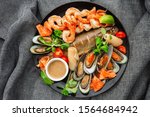 Roasted Mixed Seafood Contain Mussels, prawns, salmon, Calamari Squids and Grilled Barracuda Fish Garlic with Spicy Chili Sauce. Isolated on gray Background. Seafood and meat platter. Mediterranean