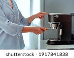 Female hands holding portafilter and making fresh aromatic coffee at home using a modern coffee maker 