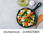 Small photo of Frozen vegetables. Frozen carrots, broccoli and cauliflower in cast iron pan ready to cook, top view with copy space