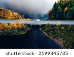 Aerial view Caravan trailer or Camper rv on the bridge over the lake in Finland. Autumn holiday trip.