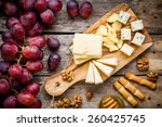 Cheese plate: Emmental, Camembert cheese, blue cheese, bread sticks, walnuts, hazelnuts, honey, grapes on wooden table