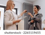 Small photo of Close up young female real estate agent giving keys to happy buyer, congratulating with purchasing apartment. Millennial woman taking in leasing new house, accommodation tenancy rental service concept