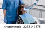 Small photo of Girl patient in the dental clinic. Teeth whitening UV lamp with dentist on background.