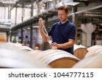 Young man testing wine in a wine factory warehouse