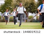 Excited Elementary School Pupils Wearing Uniform Running Across Field At Break Time