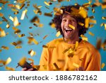 Small photo of Celebrating Young Man With Mobile Phone Winning Prize And Showered With Gold Confetti In Studio