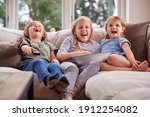 Three Children Sitting On Sofa...