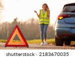 Hazard Warning Triangle Sign For Car Breakdown On Road With Woman Calling For Help