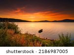 Boat in the lake at sunset. Sunset lake boat. Lake boat at sunset. Boat in lake at sunset