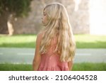 The back view of beautiful Caucasian little kid girl wearing dress standing outdoors  Studio Shoot.