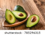 Avocado on old wooden table.Halfs on wooden bowl. Fruits healthy food concept.
