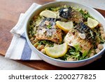 Small photo of Mackerel fish stew with pan-fried mackerel fish, chickpeas, pea shoots, garlic and Lemon. Close-up.Top view. White plate. Wooden table.