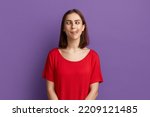 Small photo of I lost my mind. Pretty brunette girl in red t-shirt demonstrating tongue and making stupid face with crossed eyes. Looks as a crazy woman showing ridiculous grimace. Posing over purple background