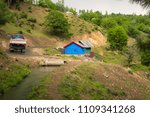 Small photo of A blue colour hut, water canal, a truck moving upslope on a road