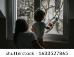 Small photo of Rainy day. Little toddler boy with his sister looking outside through wet window from his room missing mother. Siblings love, care and support. Lifestyle. Quarantine and isolation period at home