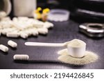 Small photo of Measuring spoon with creatine or whey, and steroid pills, food supplement, casein cocktail, muscle mass vitamin, plated, bodybuilding concept