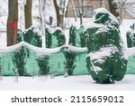 Small photo of Plants, bushes and trees in a park or garden covered with green blanket antifreeze, swath of burlap, frost protection bags or roll to protect them from frost, freeze and cold temperature