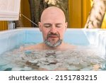 Small photo of Vilnius, Lithuania - April 30 2022: Boy or man with closed eyes ice bathing in the cold water among ice cubes. Wim Hof Method, cold therapy, breathing techniques, yoga and meditation