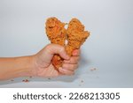hand holding fried chicken thigh on white background. closeup view