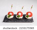 Small photo of Mini snacks with meat, vegetables and sauce. Cold appetizer. On a black serving board. On a white background. Snacks for public catering . Catering. Buffet table. Catering.