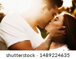 Close up side view portrait of a beautiful woman with red hair and freckles kissing with her boyfriend with eyes closed while against sunset.