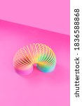 Small photo of Toy plastic rainbow on a pastel pink background. A colored spiral for play and stunts, popular in the 90s. Minimalism. The concept of toys, childhood. brightness.