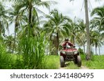 Small photo of Happy young couple in nature on a quad bike. Young man enjoying a quad bike ride in countryside. Man driving and woman enjoying the ride with her hands raised on a summer day.