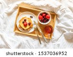 Beautiful bright breakfast in bed on a sunny morning. Toast with berries and a cup of tea on a tray. Concept of tranquility, calm, weekend, for mom, for the beloved woman, breakfast at the hotel