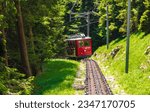 Small photo of Lucerne, Switzerland - 27th May 2022 - Close-up view of an approaching red coloured cogwheel train. It is the Pilatus Railway, the steepest rack railway in the world.