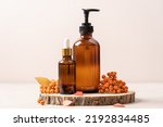 Small photo of Set of beauty cosmetics on podium from saw cut tree with autumn leaves and rowan berries. Autumn concept of skincare, fall sales, Thanksgiving cosmetic gifts