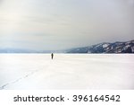 Lone stranger walking his path in the middle of snow white nowhere with distant mountains in background