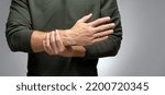 Small photo of a man with a tremor tries to keep his hand from trembling with the help of the other.
