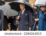 Small photo of Hamburg, Germany - March 31, 2023: King Charles III. under a black umbrella during the wreath-laying ceremony at the St. Nikolai memorial, his wife Queen Consort Camilla can be seen in background