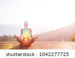 Beautiful woman sits in a pose of a half lotus on high place amazing view of the island outside, she practicing yoga meditation glowing seven all chakra eyes closed calm. Kundalini energy