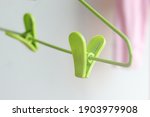 Green plastic clothes pegs on hanger with pink shirt as background, it looks like a green heart. Love and valentine day concept.