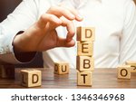 Small photo of Businessman removes wooden blocks with the word Debt. Reduction or restructuring of debt. Bankruptcy announcement. Refusal to pay debts or loans and invalidate them. Debts service relief