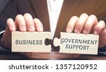 Small photo of Businessman collects puzzles with the words Business and government support. Tax relief. Protection of manufacturers in the domestic market and promotion in foreign markets. Exemption from taxes.