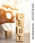 Small photo of Businessman removes wooden blocks with the word Debt. Reduction or restructuring of debt. Bankruptcy announcement. Refusal to pay debts or loans and invalidate them. Debts service relief