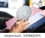 Closeup shot of truck driver holding analog tachograph disc in hands 
