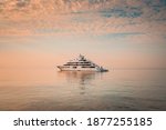 Mega yacht at anchor in a beautiful calm morning, warm light with orange and blue tones