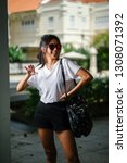 Small photo of Portrait of an unselfconscious, attractive and young Chinese Asian model girl smiling and goofing around as she poses for her photo on a street in Asia. She is tall, slim, cute and fashionable.