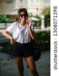 Small photo of Portrait of an unselfconscious, attractive and young Chinese Asian model girl smiling and goofing around as she poses for her photo on a street in Asia. She is tall, slim, cute and fashionable.