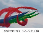 A group of aircraft performs aerobatics figure in the sky with coloured smoke. Jet airplanes is spinning around a group of planes with smoke trails