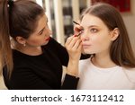 Professional makeup artist applying eye makeup on her female client