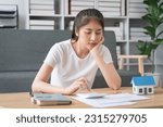 Small photo of Young woman calculating family budge,trying to save, having stressed and concentrated look.Saving money and finances concept.