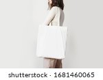 Urban mockup of tote bag. Girl holding white cotton tote bag on a white wall background. Template can be used for you design 